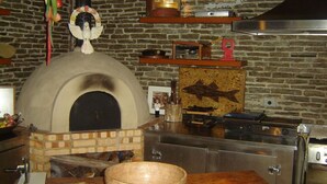 A kitchen with a brick oven, wooden shelves, and a fish mural. - Pousada Pilar (Arraial do Cabo)