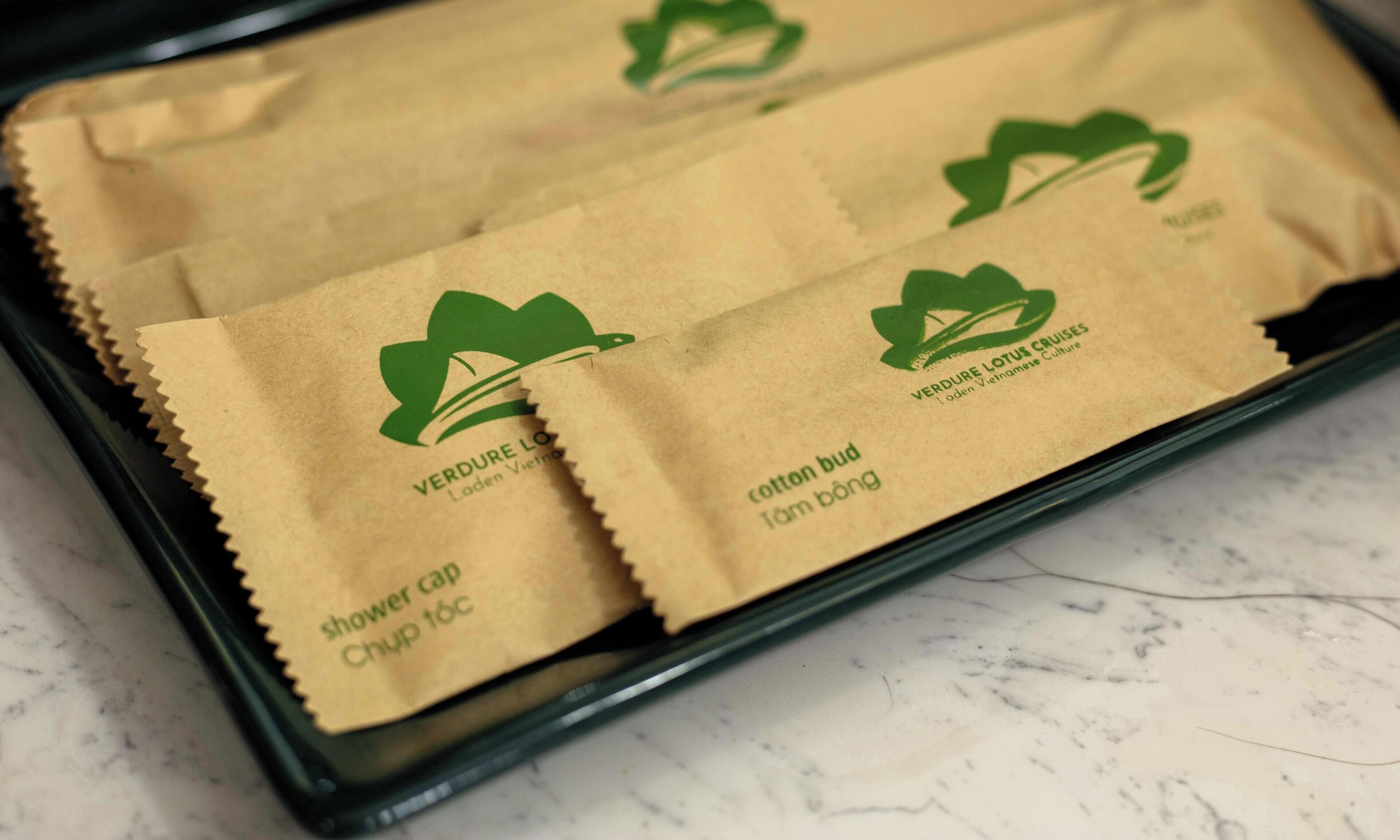 A tray with paper bags labeled 'VERDURE LOTUS CRUISES' and 'cotton bud.'