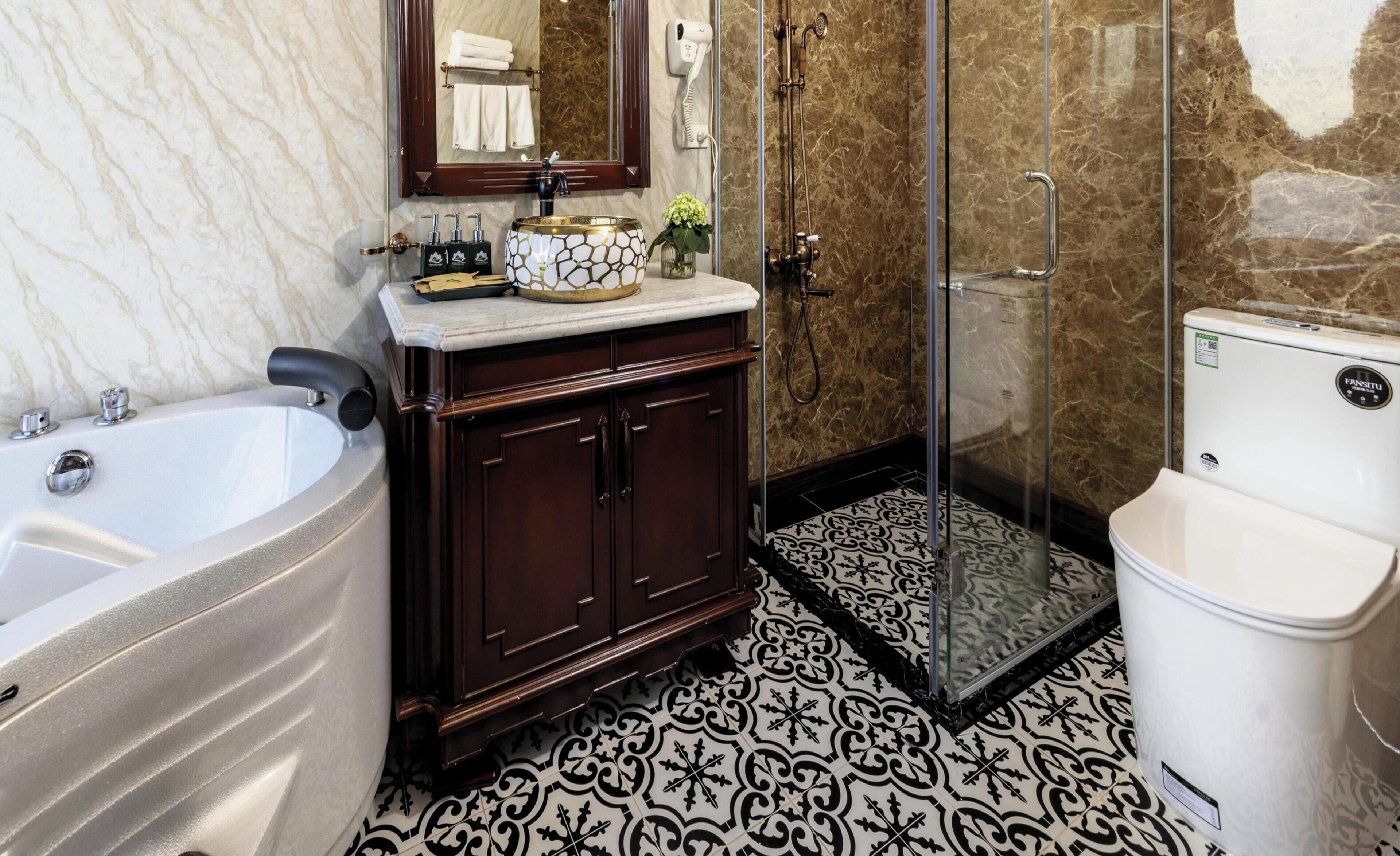 Une salle de bain avec un lavabo en marbre, une grande baignoire, une douche à parois de verre et des toilettes.