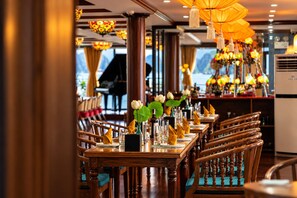 Un restaurante con mesas y sillas de madera, un piano y lámparas decorativas colgantes.