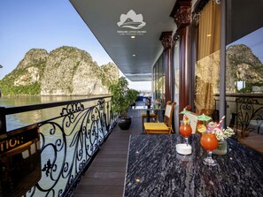 Un balcone con vista sul fiume e sulle montagne, un tavolo con bevande e un cartello per Verdure Lotus Cruises.