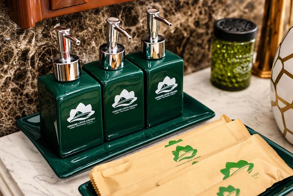 Casa de banho com dispensadores de sabonete verde, um copo verde e um tabuleiro com sacos de papel castanho.