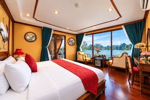 Habitación de hotel con una cama grande, un escritorio, una silla y vista a un cuerpo de agua.