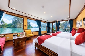 Amplia habitación con una cama grande, zona de estar y vistas a un paisaje tropical.