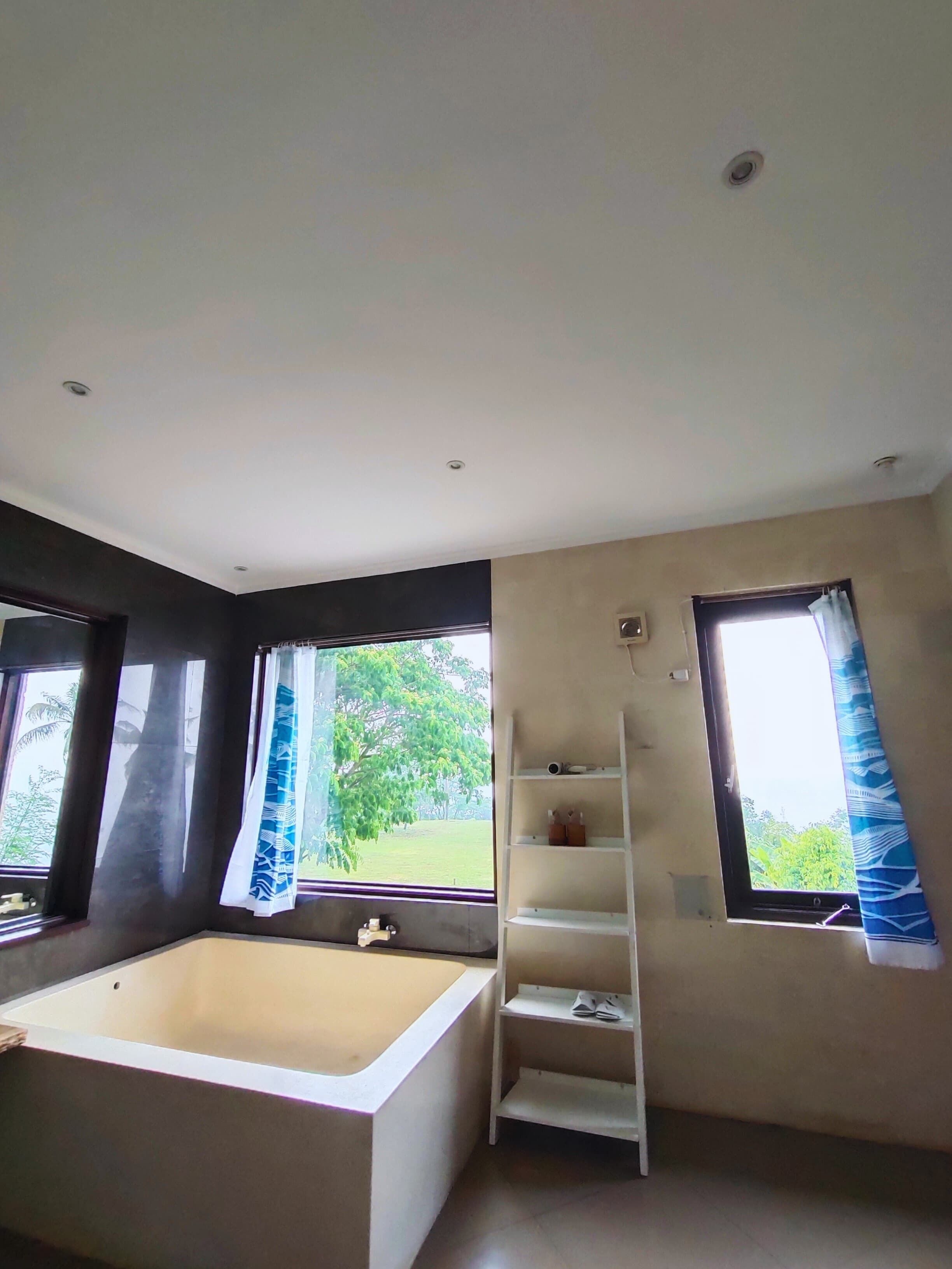 A modern bathroom with a bathtub, a shower area, and a window with curtains.