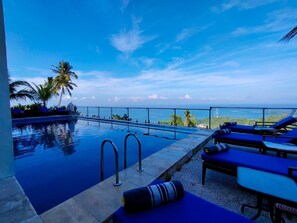 A pool with lounge chairs and a view of the ocean. - Villa Umbrella (Senggigi)