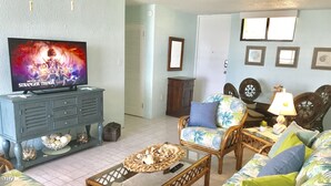 Un salon avec un téléviseur diffusant la série « Stranger Things », un fauteuil en osier, un canapé et une table basse.