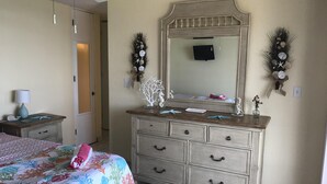 Une chambre à coucher avec un lit, une commode et un miroir.