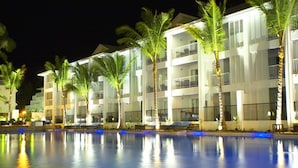 A hotel with a poolside area, palm trees, and a well-lit building facade. - Beach Club Port Douglas 3 Bedroom Luxury Apartment (Port Douglas)