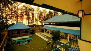 A two-story building with a blue roof and a small adjacent structure with a red roof. - Mare blu Resort (Kochi)