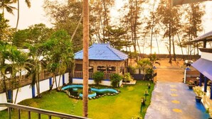 A courtyard with a blue-roofed building, surrounded by palm trees and a small water feature. - Mare blu Resort (Kochi)