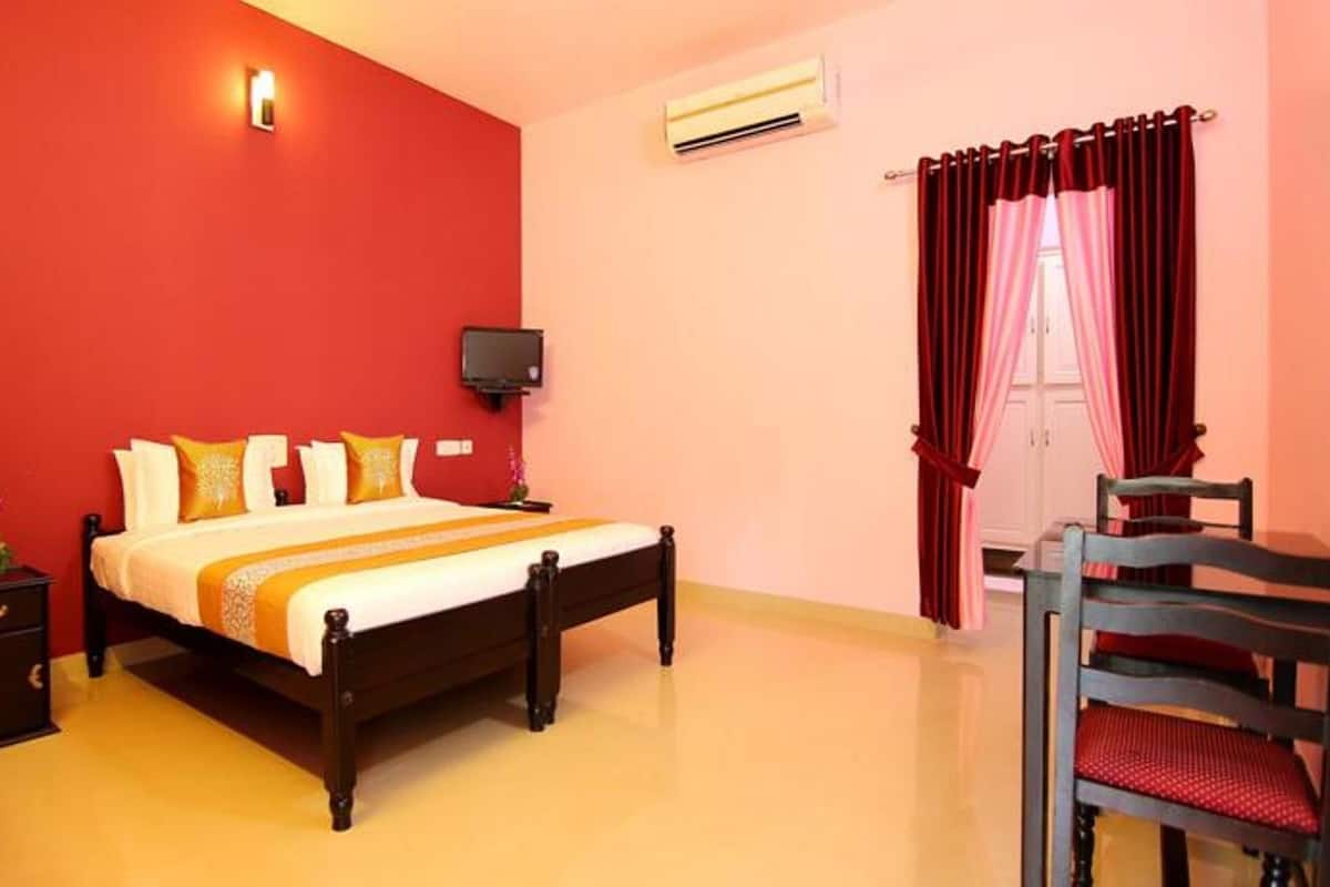 A bedroom with a bed, bedside table, TV, and a chair.