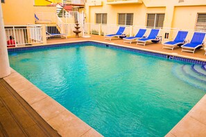 A swimming pool with blue water, surrounded by white railings and blue lounge chairs. - Fantastic Hotel (Marigot)