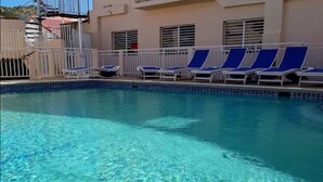 A clear swimming pool with blue lounge chairs and a white railing. - Fantastic Hotel (Marigot)