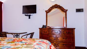 Une chambre à coucher comprenant un lit, une commode, un téléviseur et une petite table.