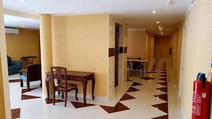 A hotel lobby with a dining area featuring a wooden table and chairs, a blue sofa, and a patterned floor. - Fantastic Hotel (Marigot)