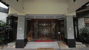 A hotel entrance with a red carpet, a 'WELCOME' mat, and a statue of a monkey.