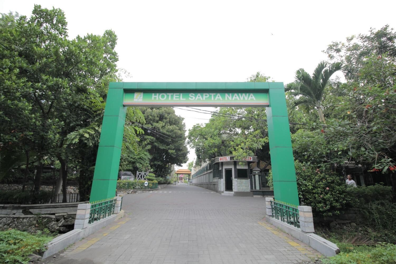 A green archway with the sign "HOTEL SAPTA NAWA" leading to a building.