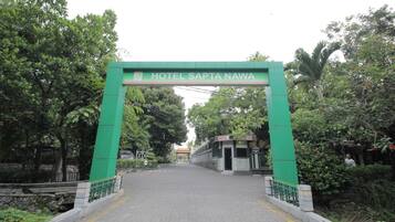 Un arco verde con el letrero "HOTEL SAPTA NAWA" que da paso a un edificio.