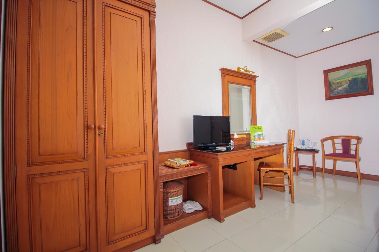 A room with a wooden desk, a television, a wicker basket, and a chair.