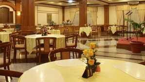 A spacious banquet hall with multiple round tables, each with a number sign, and chairs arranged around them.