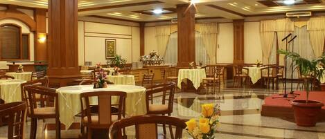 A spacious banquet hall with multiple round tables, each with a number sign, and chairs arranged around them.