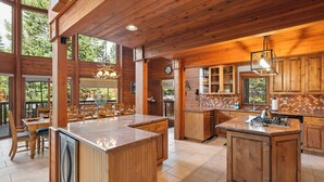 A spacious kitchen with wooden cabinetry, a large island, and a dining area with wooden chairs and a table. - Donner Lake Retreat | Queen Suite, Games, Near Lake, Golf & Trails (Truckee)