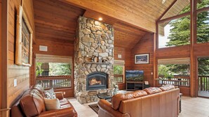 A cozy living room with a stone fireplace, leather sofas, and a TV. - Donner Lake Retreat | Queen Suite, Games, Near Lake, Golf & Trails (Truckee)