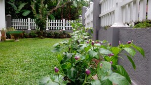 Un jardín bien cuidado con cerca blanca de piquetes, césped verde exuberante y plantas con flores.