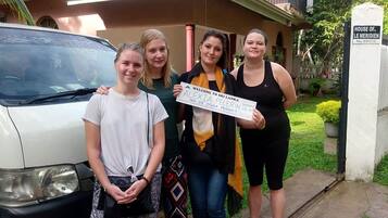 Four people standing in front of a house with a sign that reads "HOUSE OF.. LE MERIDIEN No.89/C/2".
