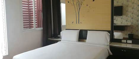 A hotel room with a large bed, a nightstand, a wall-mounted TV, and a window with blinds.