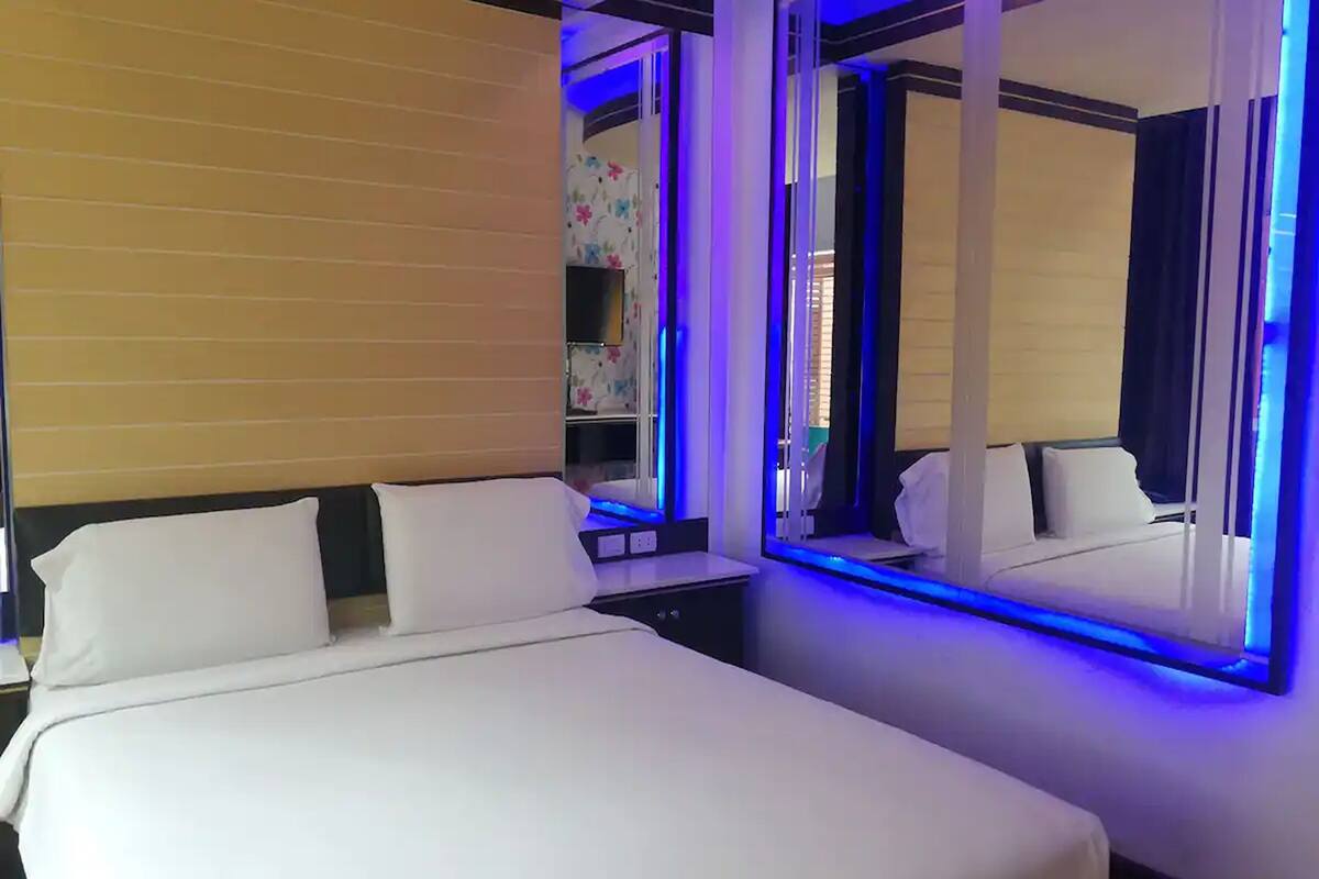 A hotel room with a large bed, a bedside table, a mirror, and a window with curtains.