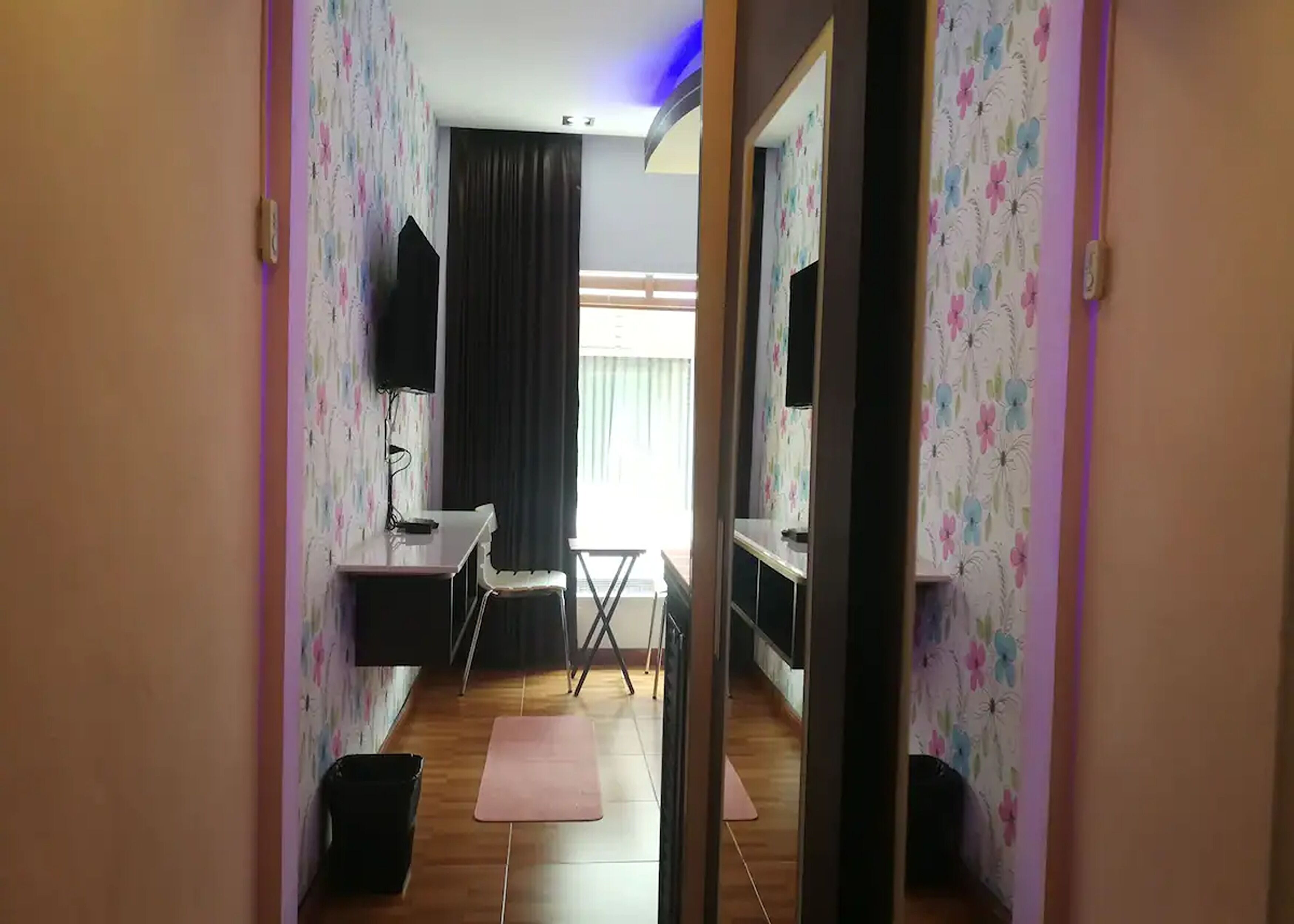 Habitación con escritorio, silla, televisor y vista a una ventana con cortinas.