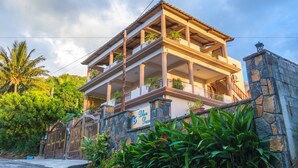 Un edificio de varios pisos con fachada de piedra, balcones con plantas y un letrero que dice "Blue Pearl".