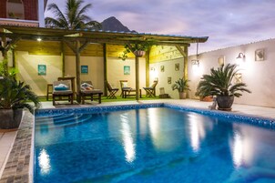 Una piscina con sillones de playa y un área de estar techada.