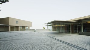 A modern building with a paved courtyard, large glass windows, and a minimalist design. - Atami Club Geihinkan (Atami)