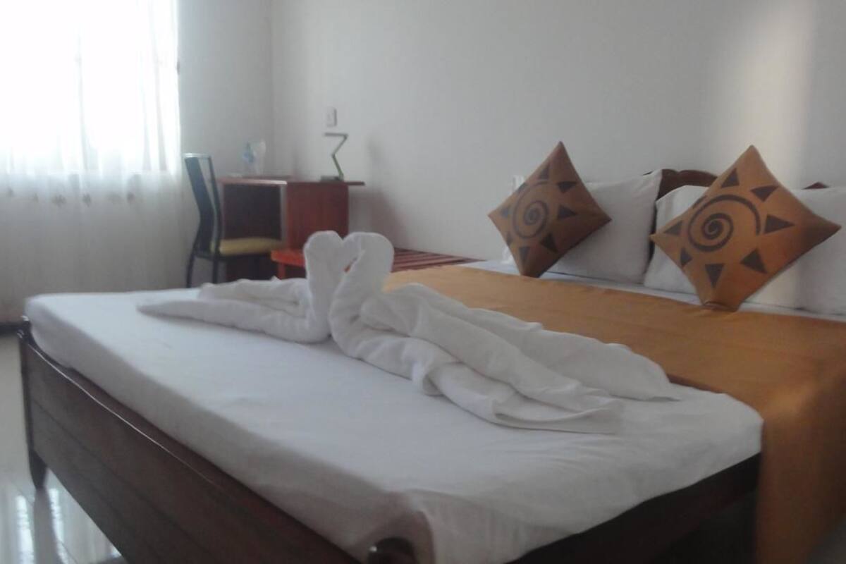 A hotel room with a neatly made bed, a desk, and a chair.