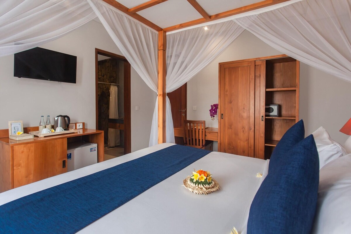 A bedroom with a bed, a desk, a wardrobe, and a television.