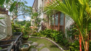 A garden with a stone pathway, various plants, and a bird feeder. - Ning Villa Ubud by GenuineHost (Ubud)