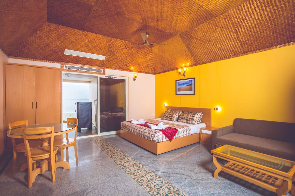 Une pièce comprenant un lit, un canapé, une table à manger avec des chaises, un ventilateur de plafond et un tableau au mur.