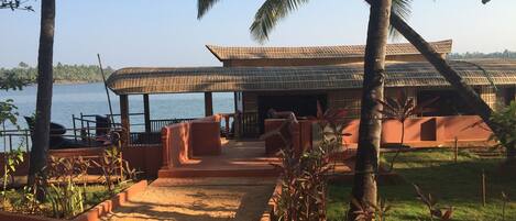 A beachside resort with a thatched-roof structure, a sandy pathway, and a view of the sea.