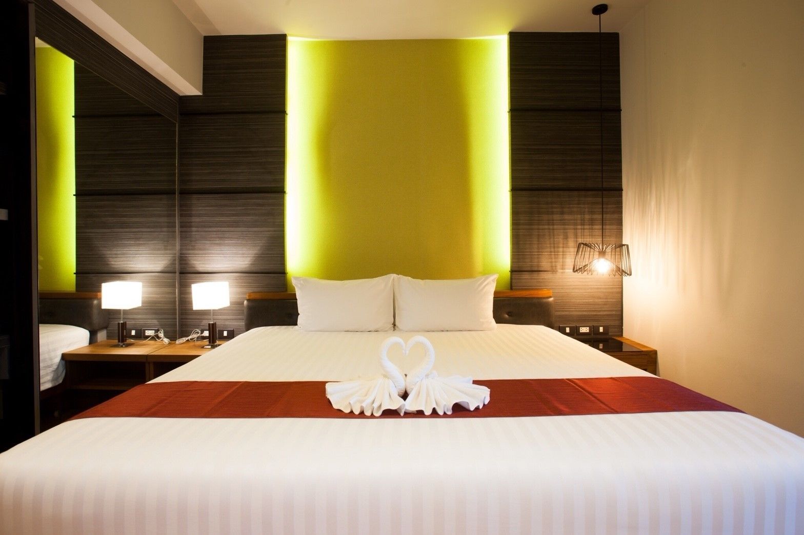 Una habitación de hotel con una cama grande, dos mesitas de noche con lámparas y un aplique de pared.