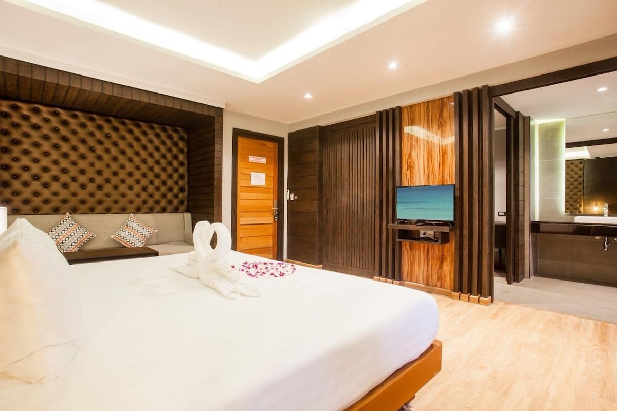 Une chambre d’hôtel moderne dotée d’un grand lit, d’une télévision et d’une salle de bain avec un miroir et un lavabo.