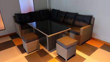 Un canapé modulable, accompagné d’une table basse au plateau en verre et de poufs assortis, le tout disposé sur un sol à carreaux.