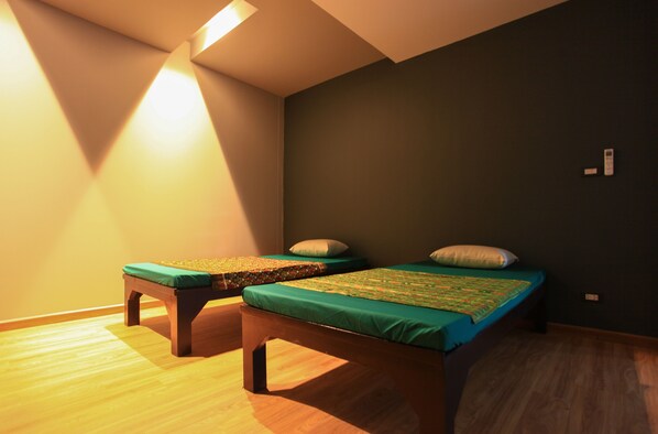 A room with two beds, wooden flooring, and a slanted ceiling.
