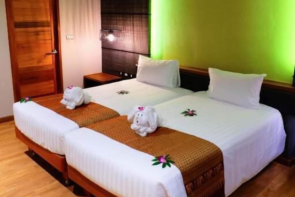 Une chambre d’hôtel avec un grand lit, un plancher en bois, un mur d’accent vert et une porte en bois.
