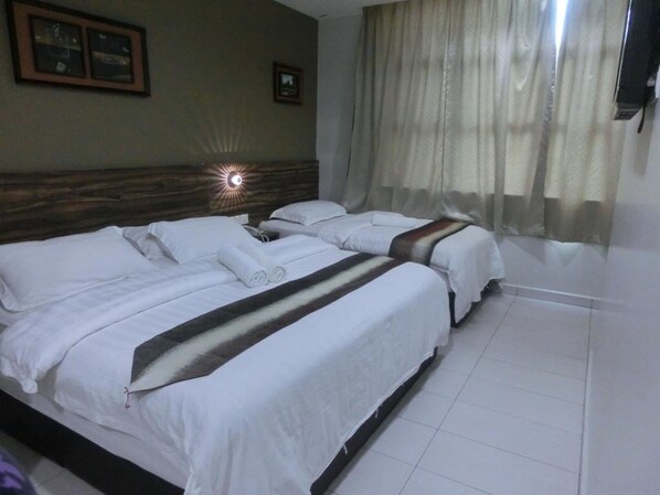 A hotel room with two beds, a wooden headboard, a large window with curtains, and a wall-mounted TV. - BG Business Hotel (Bukit Mertajam)