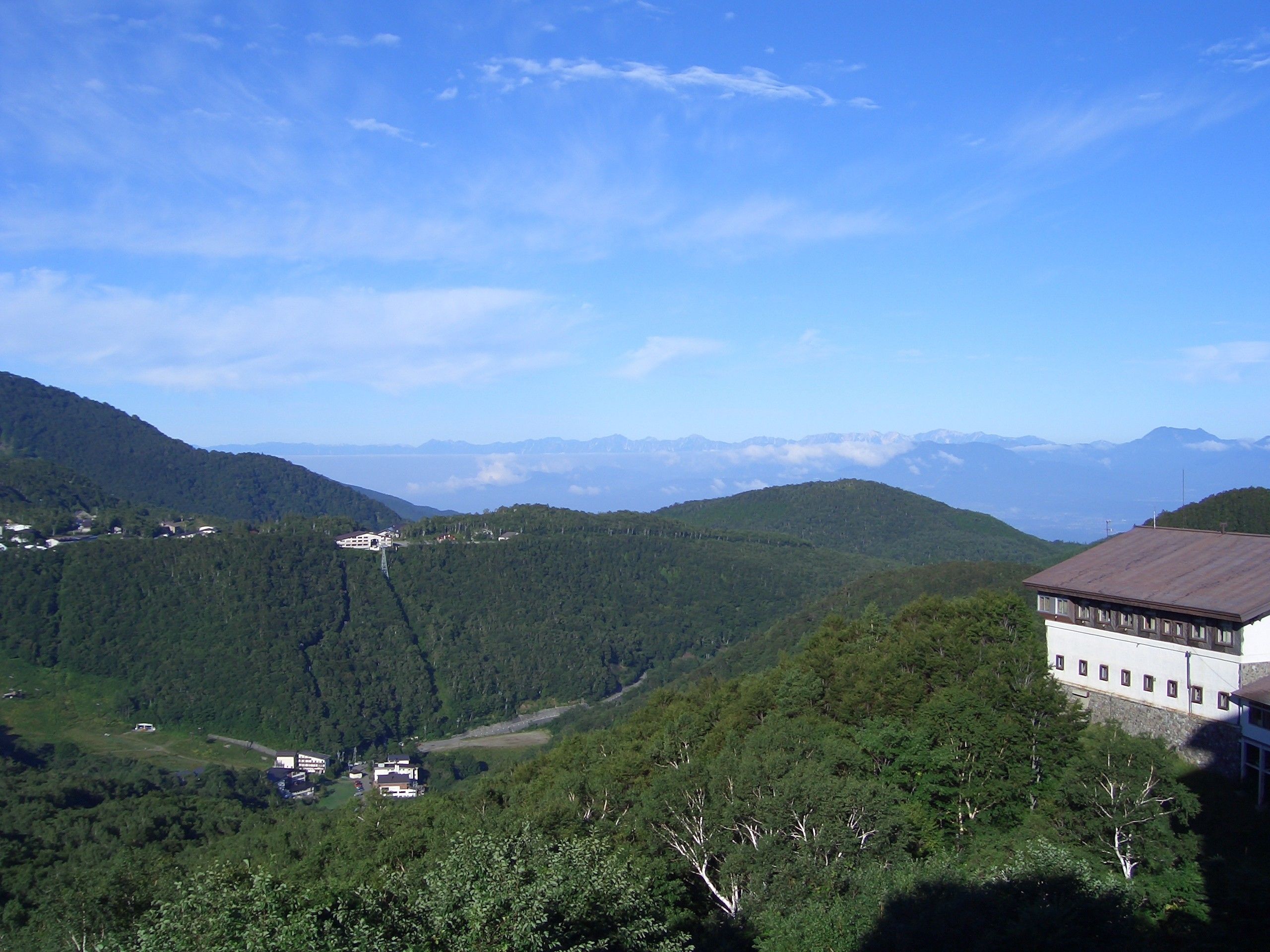 Un paysage montagneux avec un bâtiment doté d’un toit plat et d’une façade blanche.