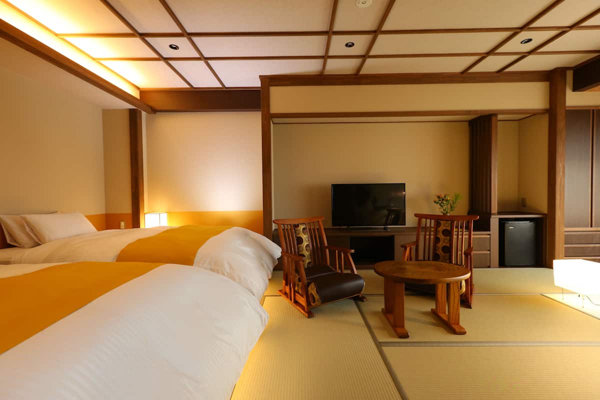 Habitación de hotel con dos camas, televisor, una mesita y zona de estar.