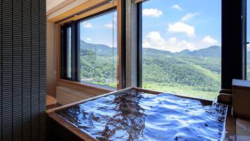 A hot tub with a view of a mountainous landscape through large windows.